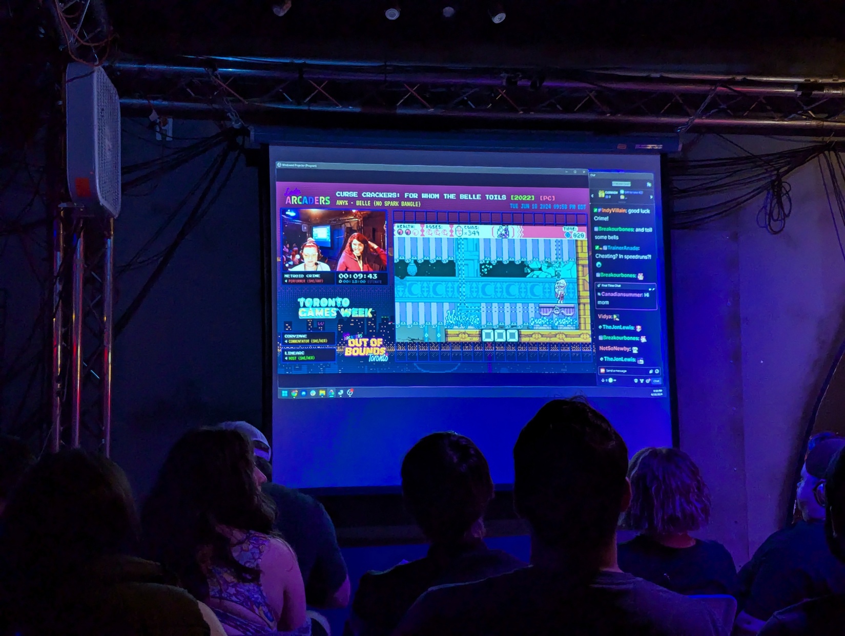 A crowd watches a speedrun on a projector screen.