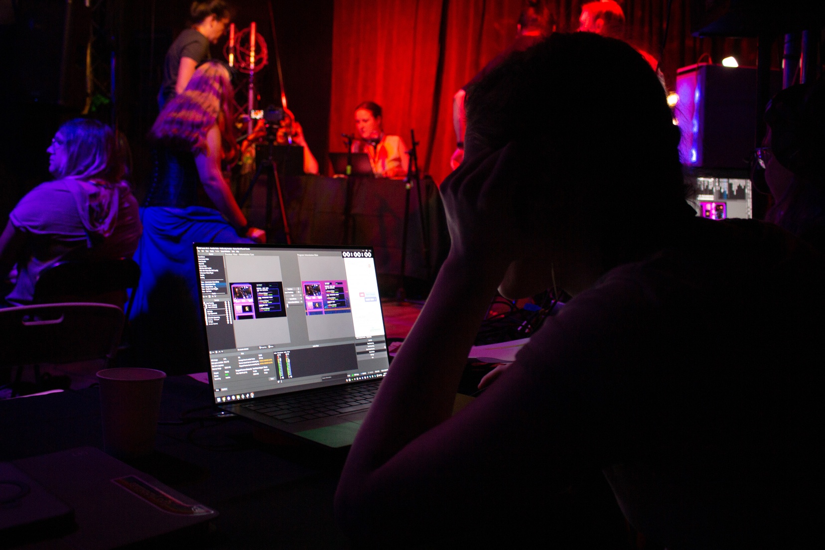 A woman sits at a computer running tech for our in person event.